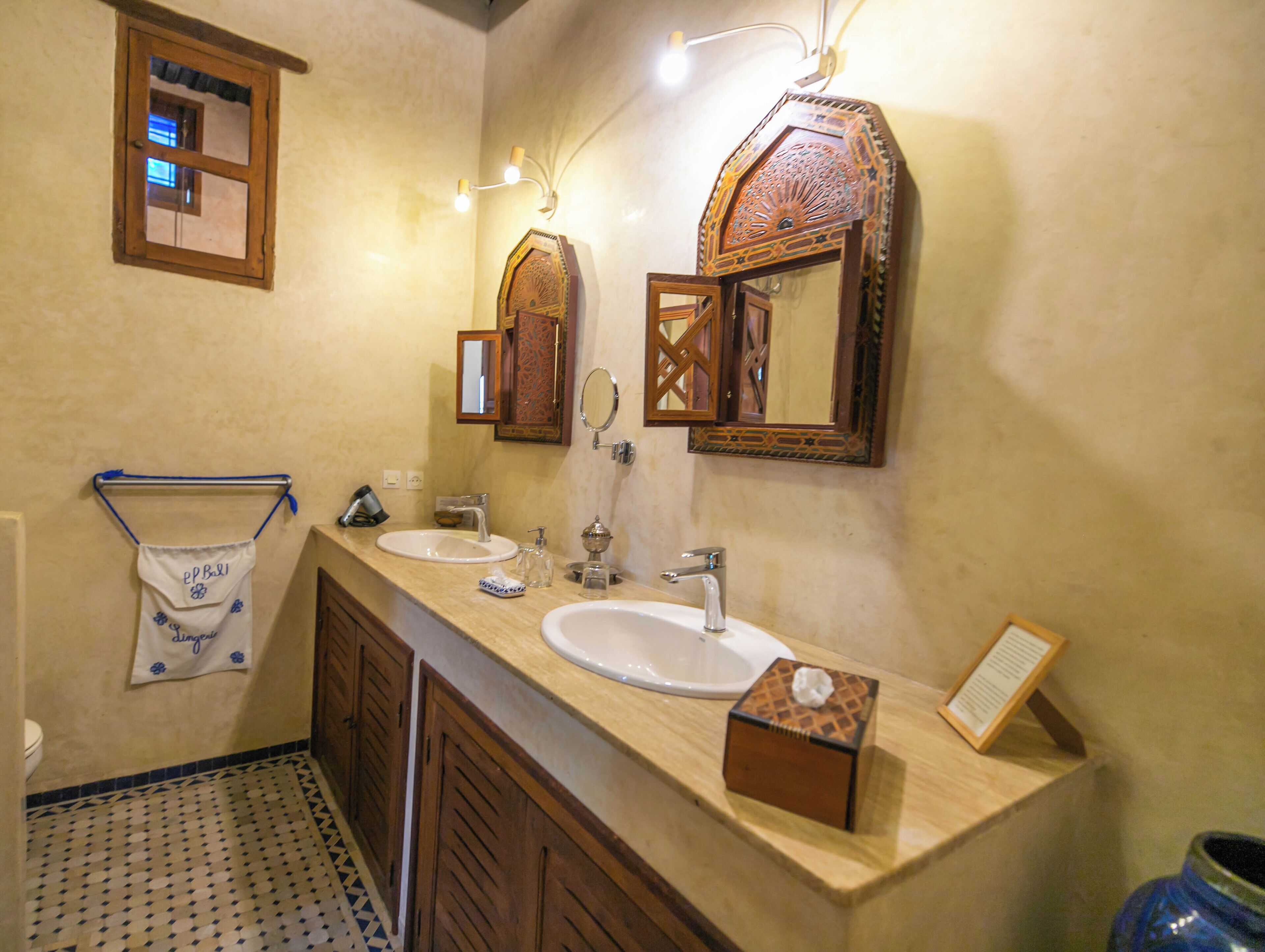 A bathroom with two sinks, a towel rack, a mirror, and a small wooden box on the counter.