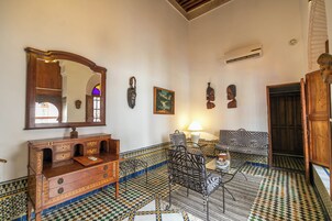 Una habitación con piso a cuadros, un mueble de madera, un sofá estampado con cebra y un espejo.