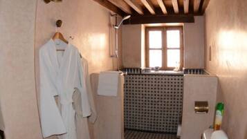 Un baño con ducha, una toalla colgada en la pared y un inodoro.