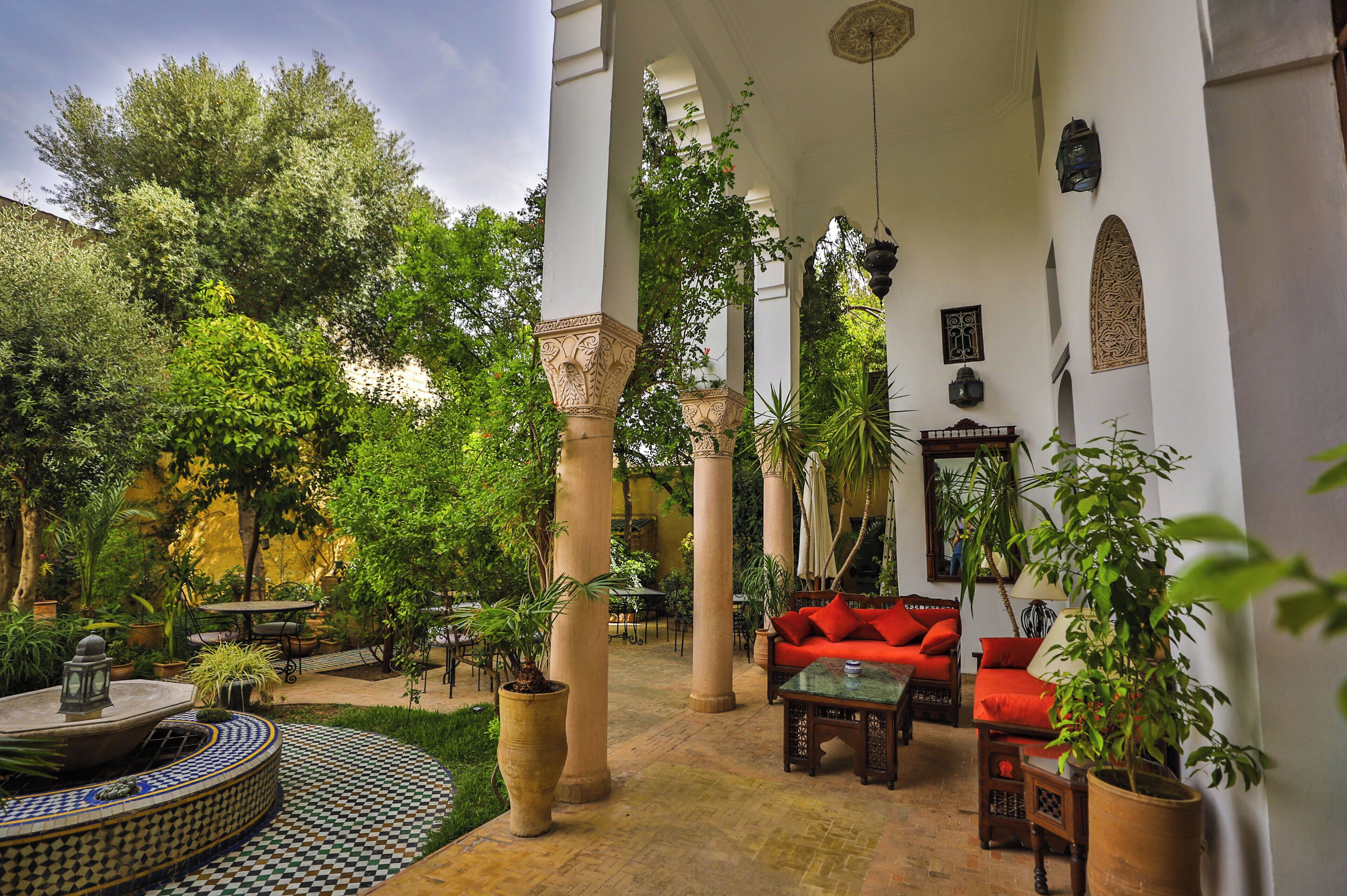 A courtyard with a fountain, seating areas, and potted plants.