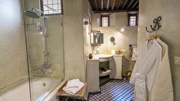 A bathroom with a glass-enclosed shower, a bathtub, a sink, and a mirror.