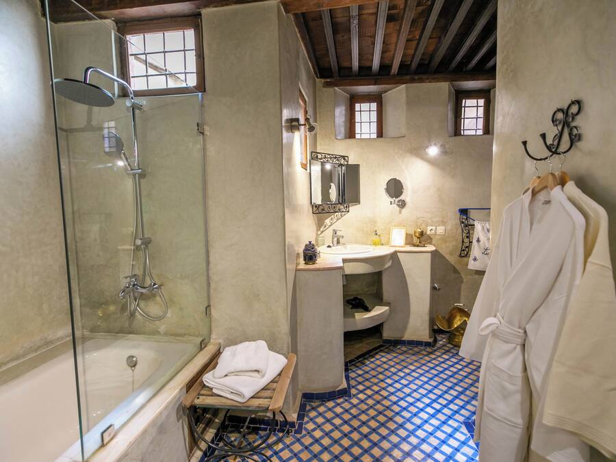 A bathroom with a glass-enclosed shower, a bathtub, a sink, and a mirror.