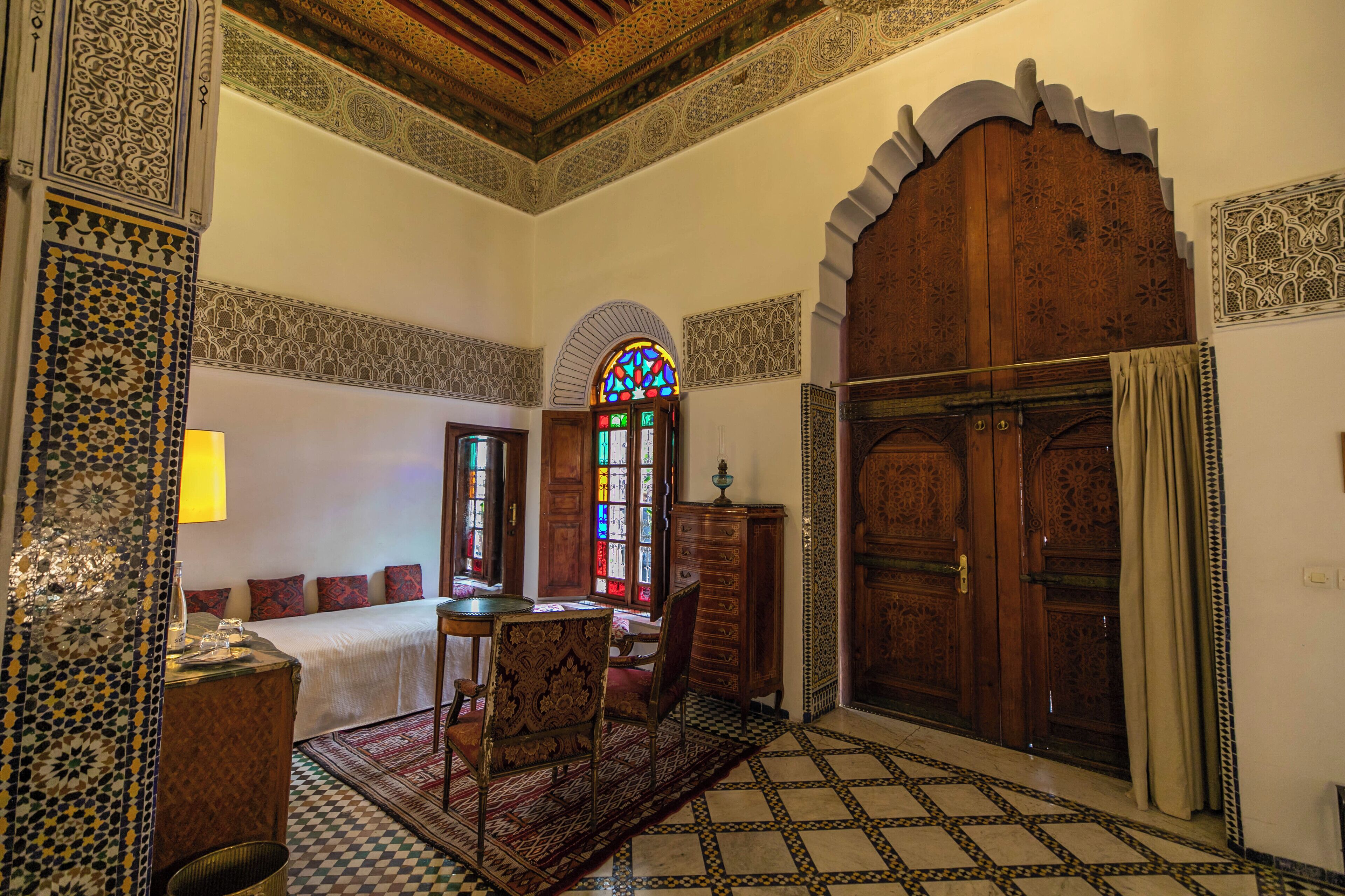 Una habitación tradicional con cama, un aparador de madera, una mesa y una silla.