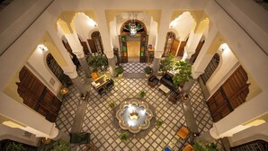An ornate courtyard with a central fountain, surrounded by seating areas and potted plants.
