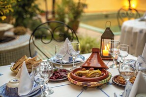 A dining table set with Moroccan dishes, glasses, and a candle. - Ryad Mabrouka (Fes)