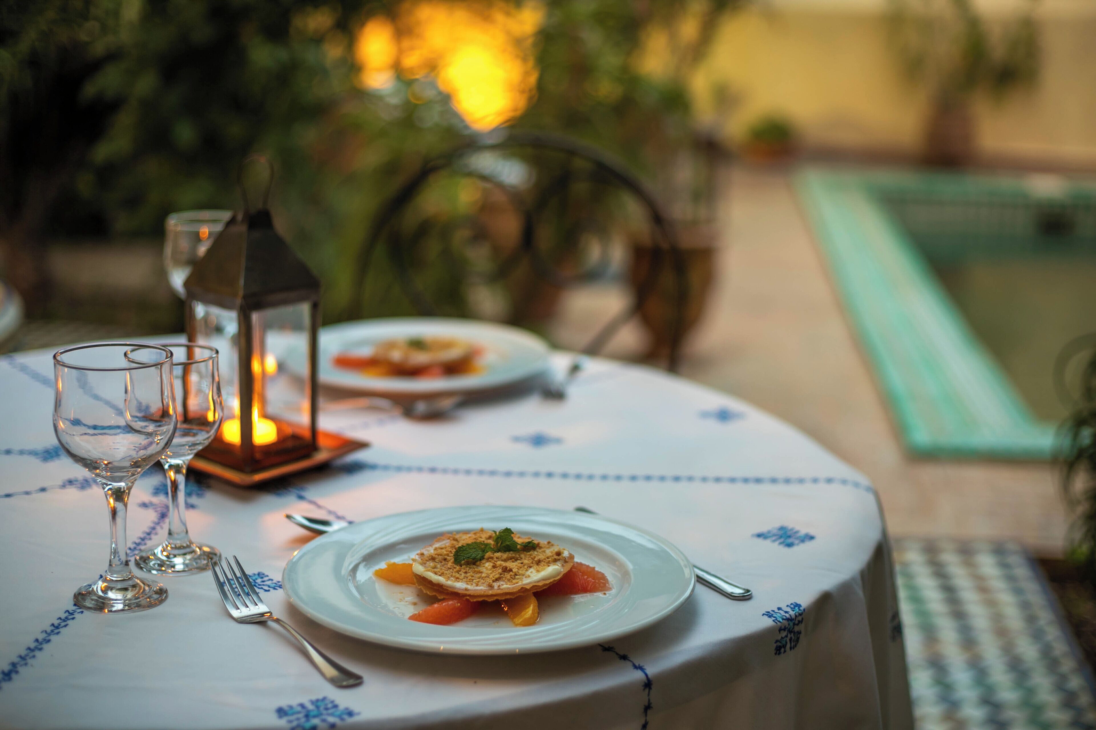 A table set for dining outdoors with a candle and a lantern.