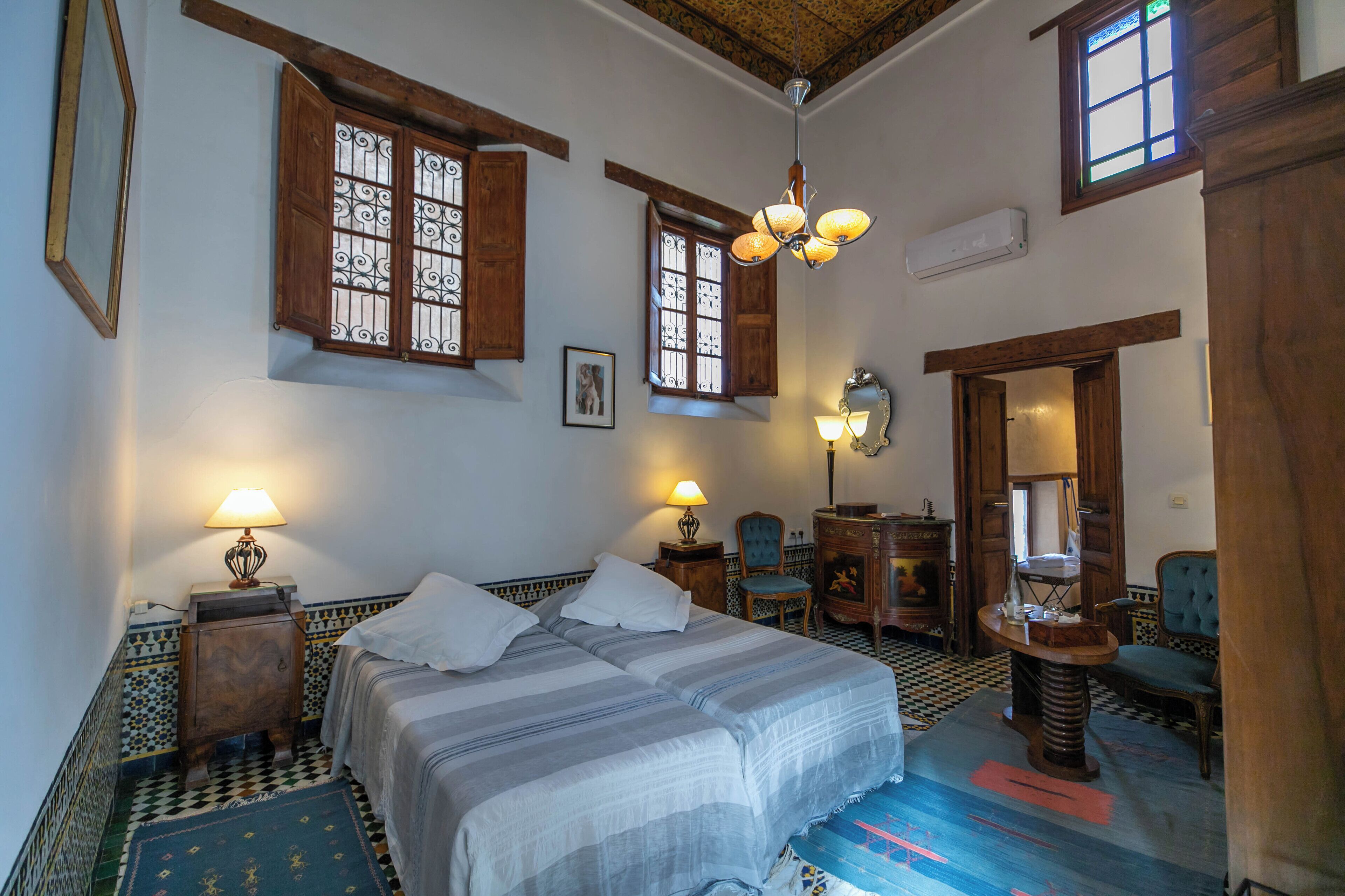 Une chambre avec un lit, deux tables de chevet, une chaise, un bureau et un miroir.