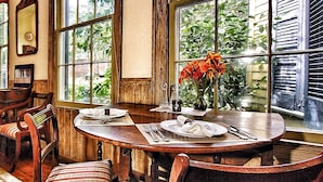 A dining area with a round table, chairs, and a vase of flowers. - GardenSong B&B (Natchez)