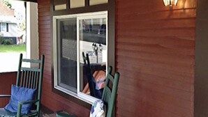 A porch with two rocking chairs, a window, and a wall-mounted light fixture. - River House Lodge (Rowlesburg)