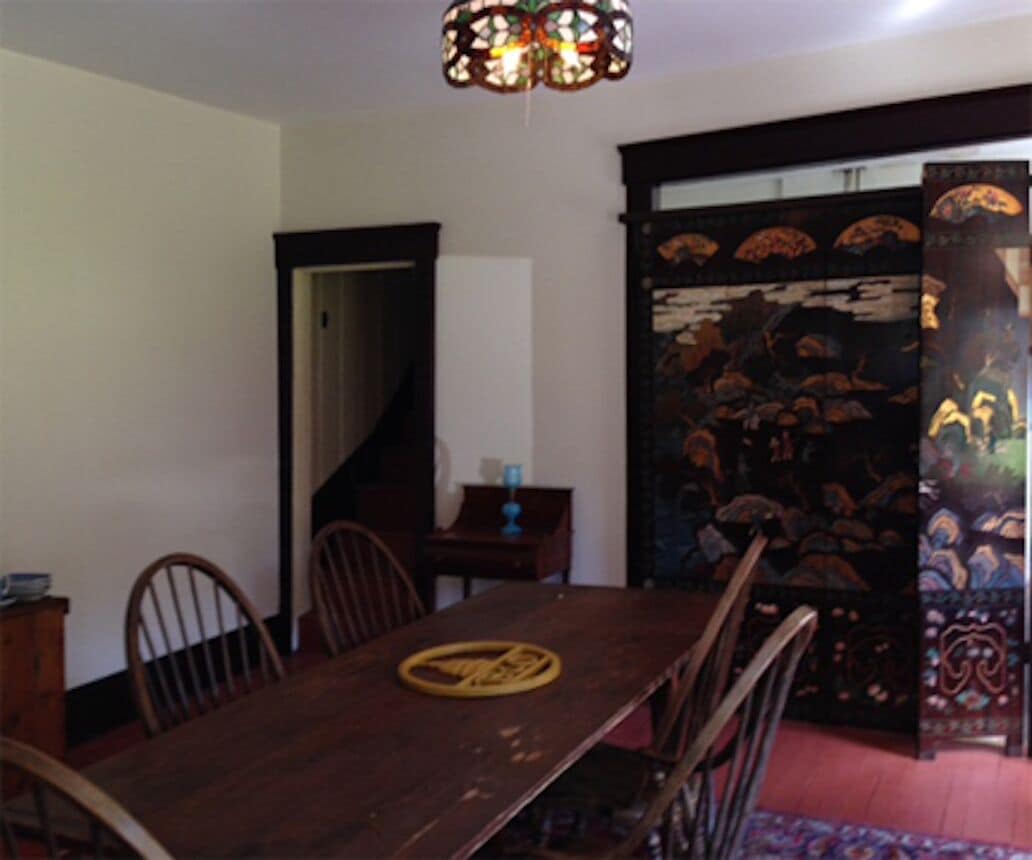 Un comedor con mesa y sillas de madera, una araña y una puerta decorativa.