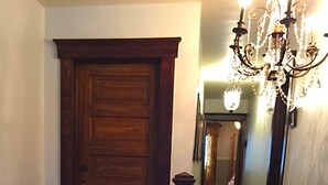 A wooden staircase with a dark handrail and a chandelier above. - River House Lodge (Rowlesburg)