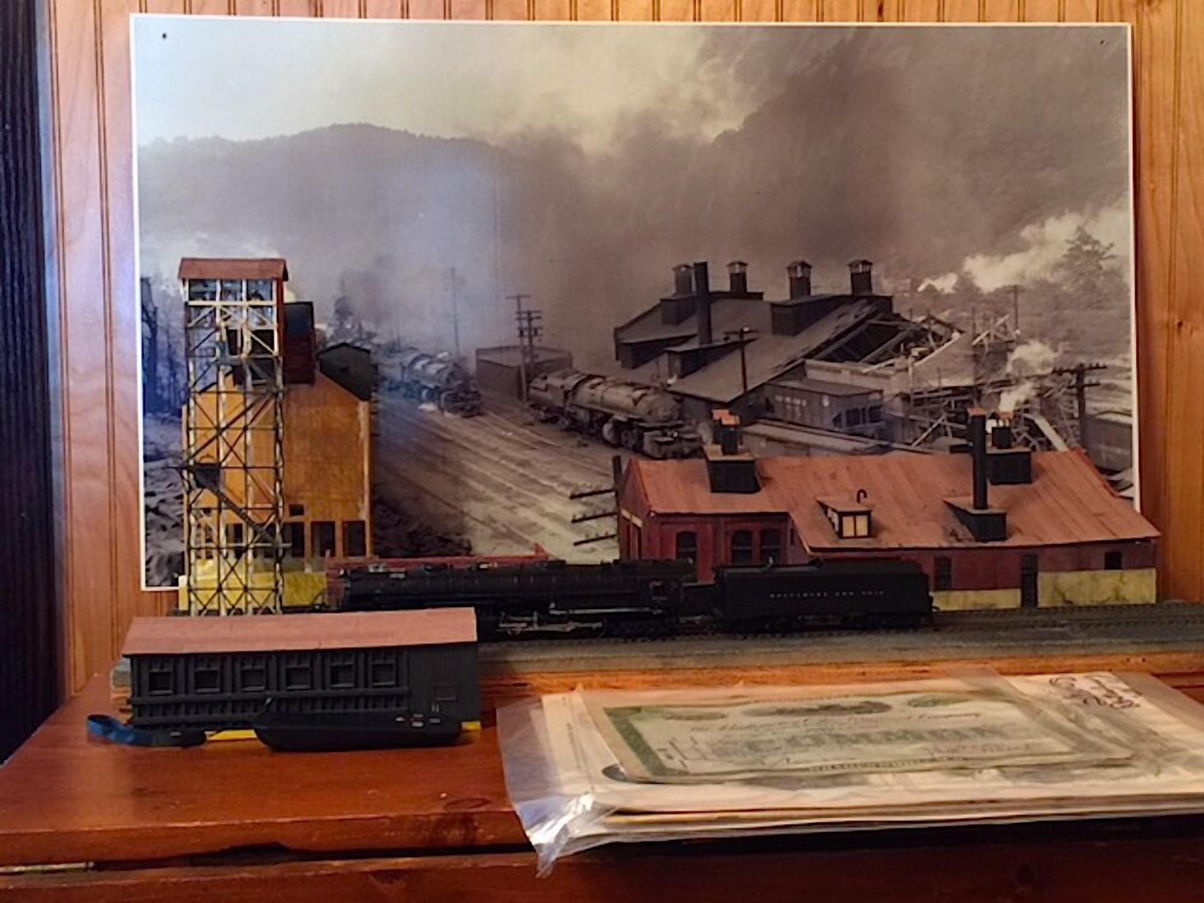 Un ensemble de trains miniatures comprenant une locomotive et des bâtiments, le tout installé sur une table en bois.