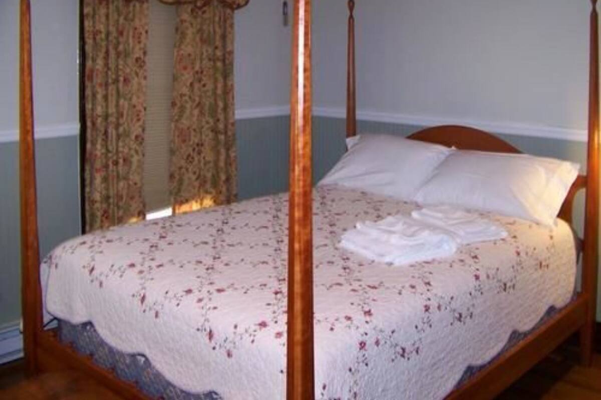 A four-poster bed with a floral bedspread and white pillows.