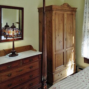 Une commode en bois avec des tiroirs, un miroir et une lampe en vitrail.