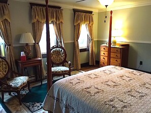 Une chambre à coucher avec un lit à baldaquin, une commode, une chaise et une table avec une lampe.