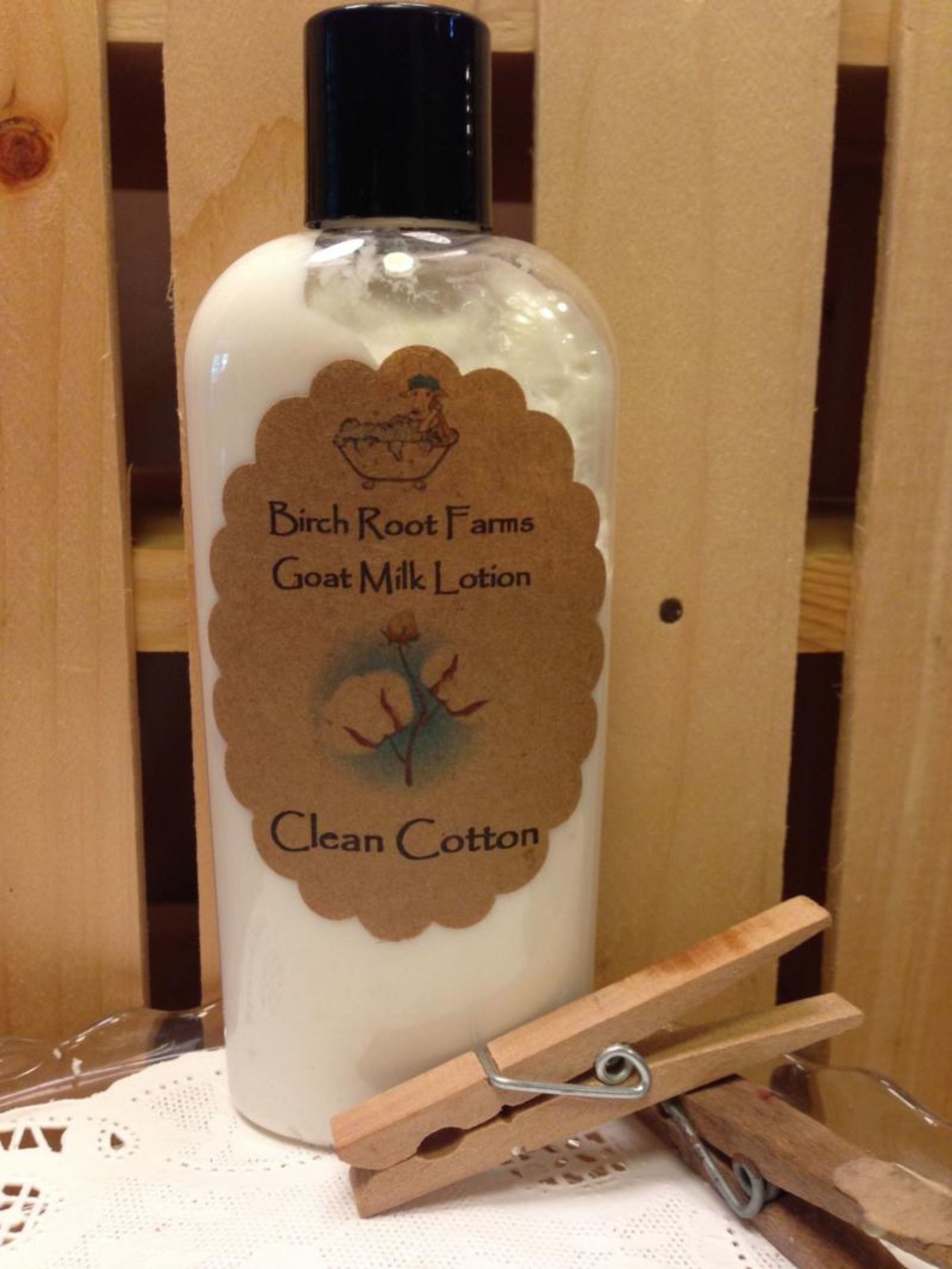 A bottle of Birch Root Farms Goat Milk Lotion with a label featuring a cotton plant illustration.