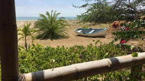 Ein Strand mit einem Boot, Palmen und einem Bambuszaun.