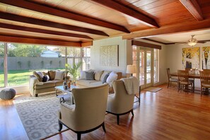 A spacious living room with a wooden ceiling, a sofa set, a dining table, and a view of the backyard. - PX001 3 Bedroom Apartment By Senstay (Phoenix)