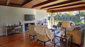 A living room with wooden flooring, a fireplace, a television, and a view of a backyard. - PX001 3 Bedroom Apartment By Senstay (Phoenix)