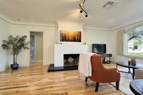A living room with a fireplace, a television, and a large window.