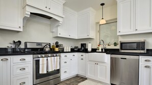 A modern kitchen with white cabinets, stainless steel appliances, and a herringbone-patterned floor. - PX002 4 Bedroom Apartment By Senstay (Phoenix)