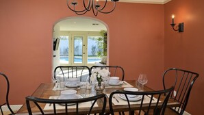 A dining room with a wooden table set for four, black chairs, a chandelier, and a view of a swimming pool through an archway. - PX002 4 Bedroom Apartment By Senstay (Phoenix)
