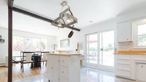 A spacious kitchen with white cabinets, a wooden countertop, and a hanging pot rack. - SH001 5 Bedroom Holiday home By Senstay (Sagaponack)