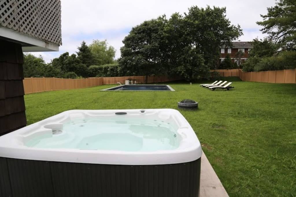 Um quintal com hidromassagem, uma piscina pequena e espreguiçadeiras.