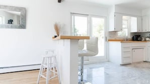 A modern kitchen with white cabinets, a wooden countertop, and a bar stool. - SH001 5 Bedroom Holiday home By Senstay (Sagaponack)