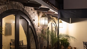 Un patio con pared de ladrillo, puerta de madera y una planta en maceta.