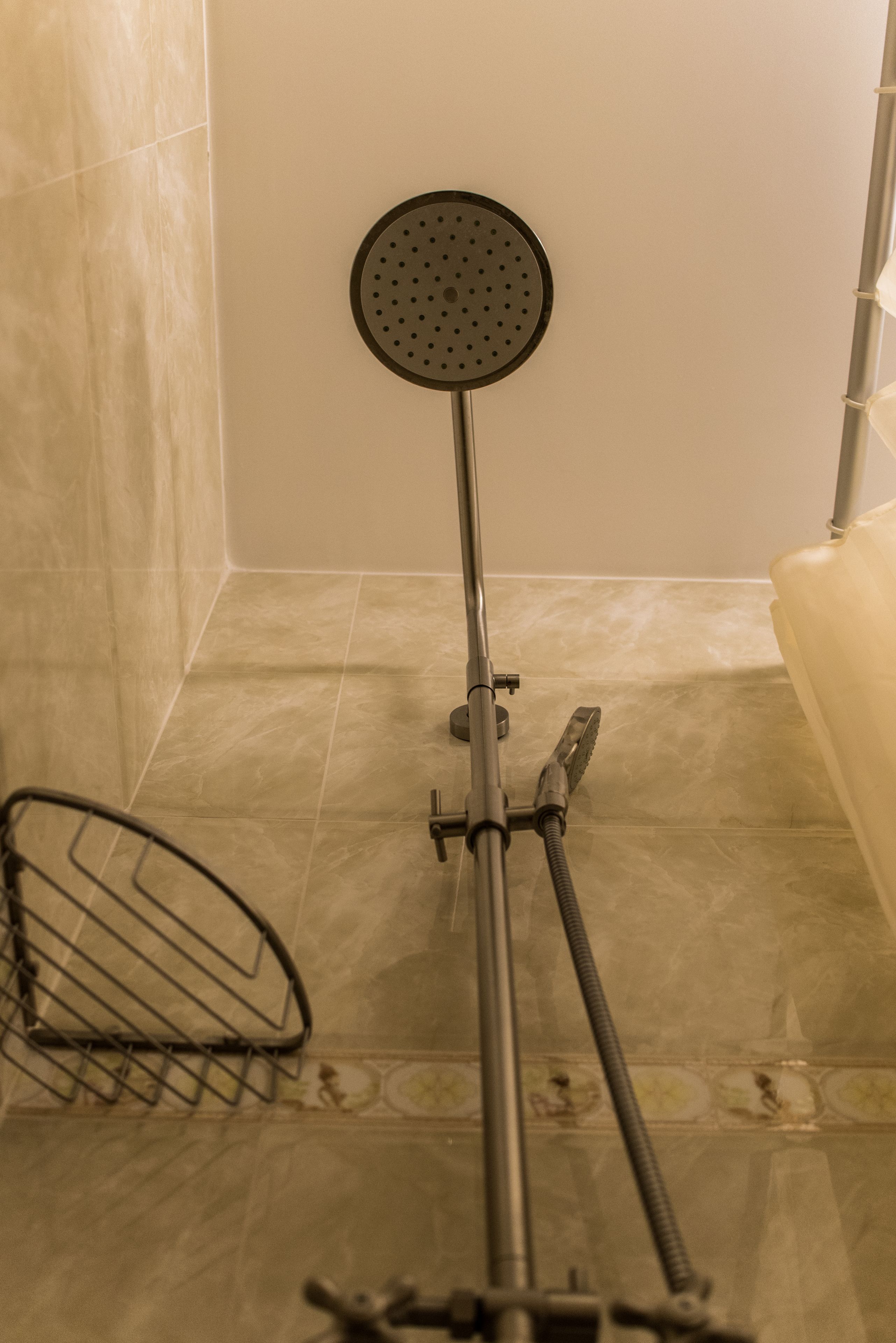 A bathroom with a shower, a metal grab bar, and a floor drain.