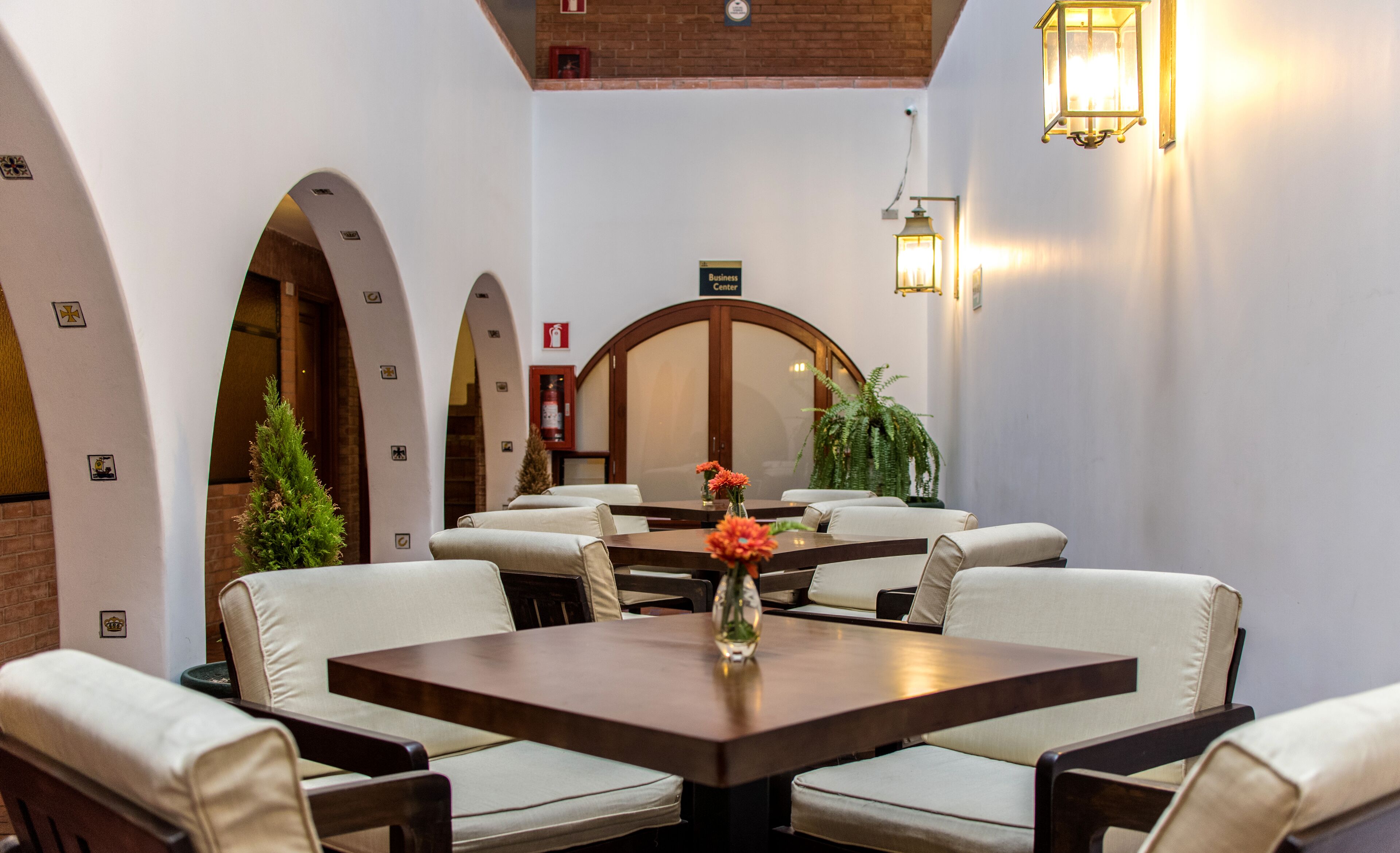 A restaurant with a central table surrounded by chairs, a large mirror, and wall-mounted lights.