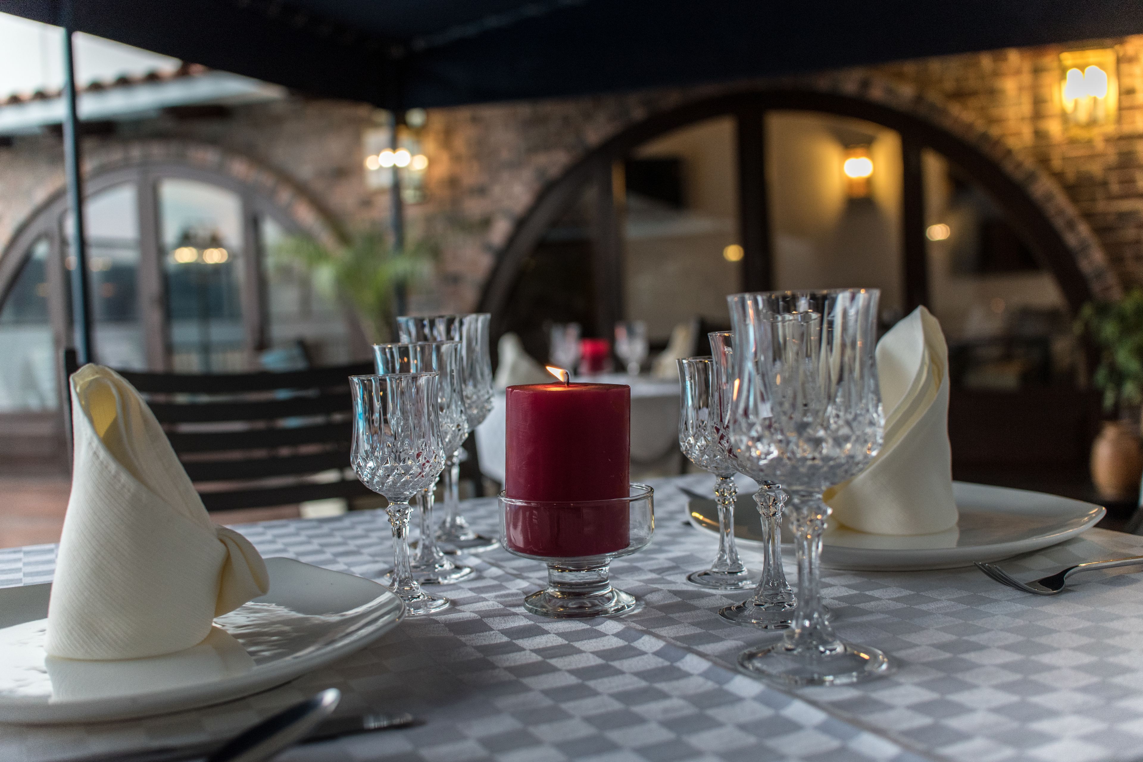 A table set for dining with a candle centerpiece, clear glassware, and white napkins.