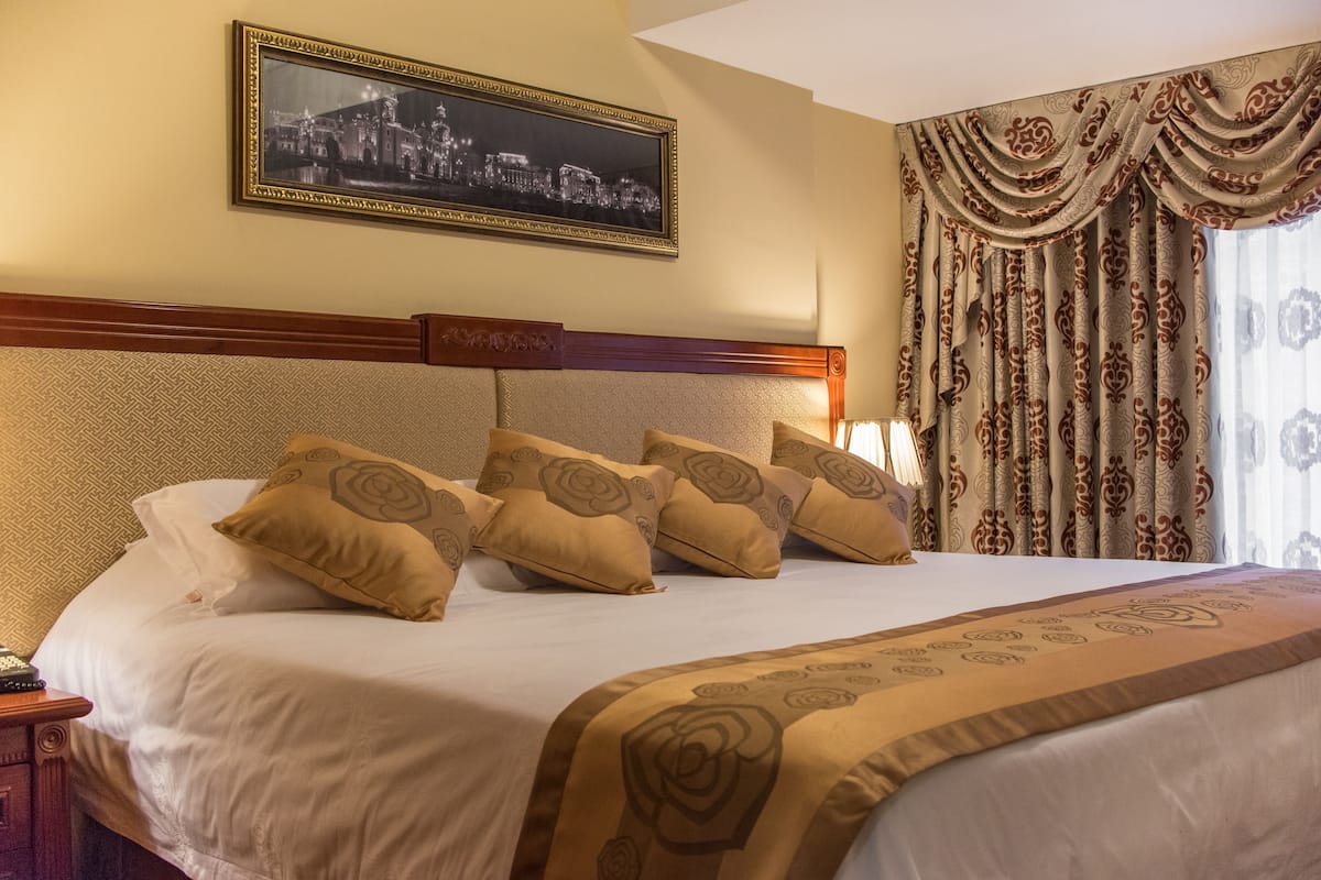 Una habitación de hotel con una cama grande, un cabecero de madera y un cuadro enmarcado en la pared.