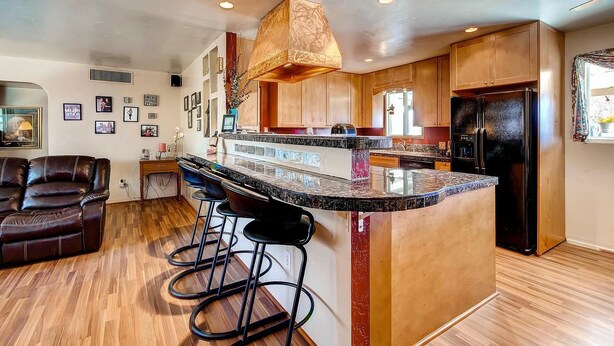 A modern kitchen with a central island, bar stools, wooden cabinets, and a black refrigerator. - PX008 4 Bedroom Apartment By Senstay (Scottsdale)