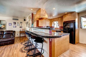 A modern kitchen with a central island, bar stools, wooden cabinets, and a black refrigerator. - PX008 4 Bedroom Apartment By Senstay (Scottsdale)