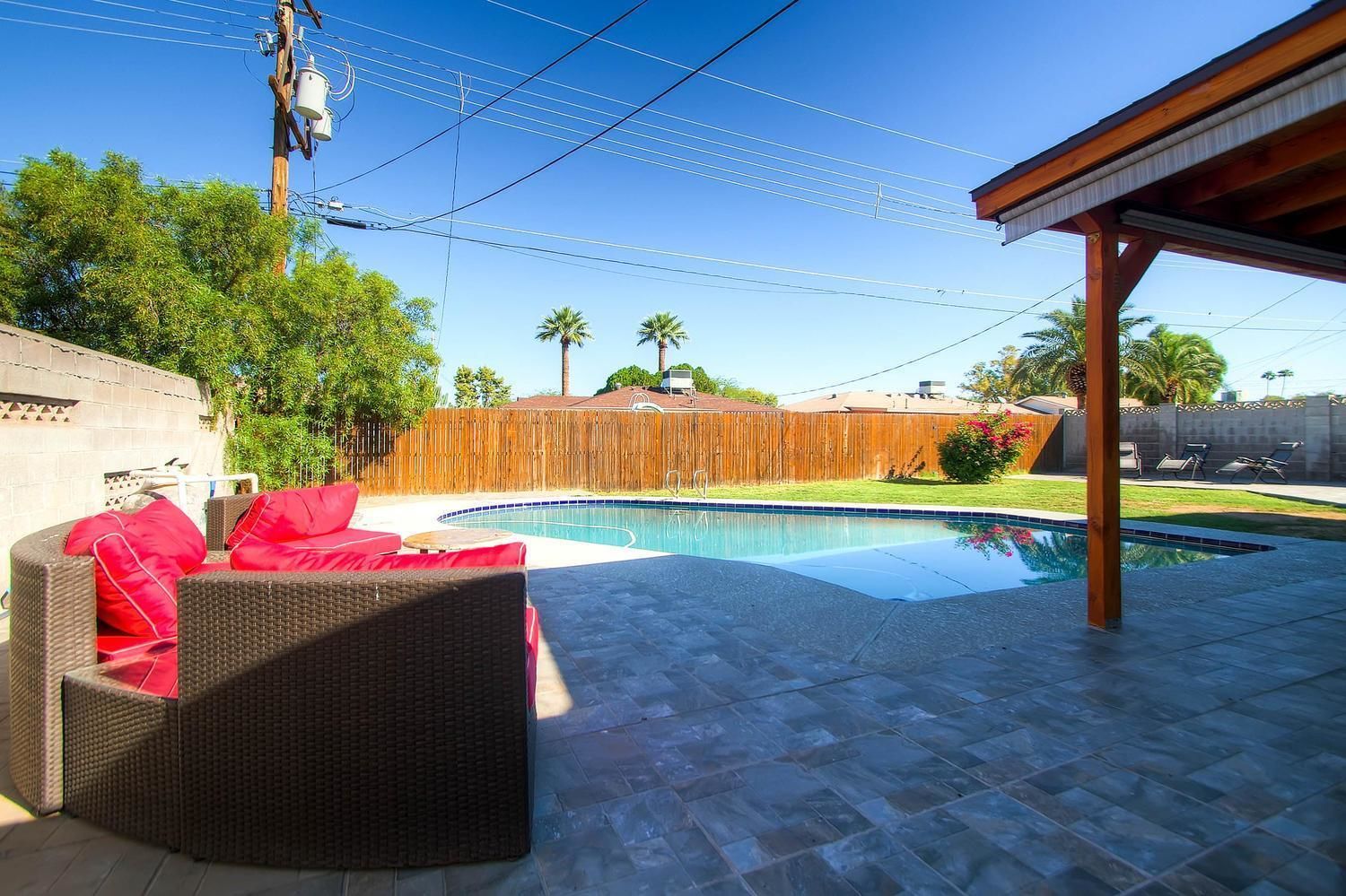 A backyard with a swimming pool, outdoor furniture, and a wooden fence.