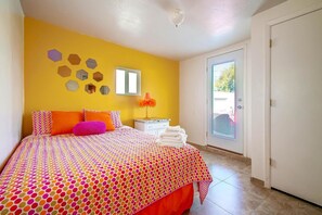 Un dormitorio con cama, mesita de noche, ventana y puerta.