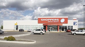 A drug store with a large sign, a parking lot, and several cars parked in front. - Elegant Suite (Saskatoon)