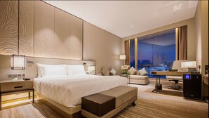 A modern hotel room with a large bed, a desk, and a view of the cityscape. - Golden Eagle Summit Hotel Nanjing China (Nanjing)