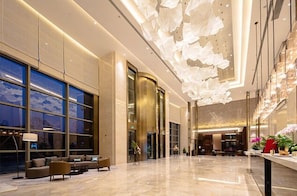 Eine geräumige Lobby mit modernem Design, ausgestattet mit einer großzügigen Sitzecke, einem Empfangstresen und einer dekorativen Decke.