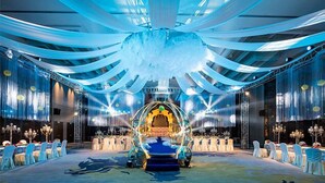 A banquet hall with a central stage, rows of white chairs, and a chandelier. - Golden Eagle Summit Hotel Nanjing China (Nanjing)