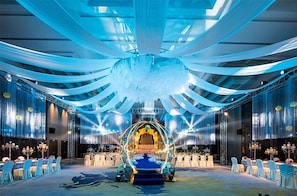 A banquet hall with a central stage, rows of white chairs, and a chandelier. - Golden Eagle Summit Hotel Nanjing China (Nanjing)