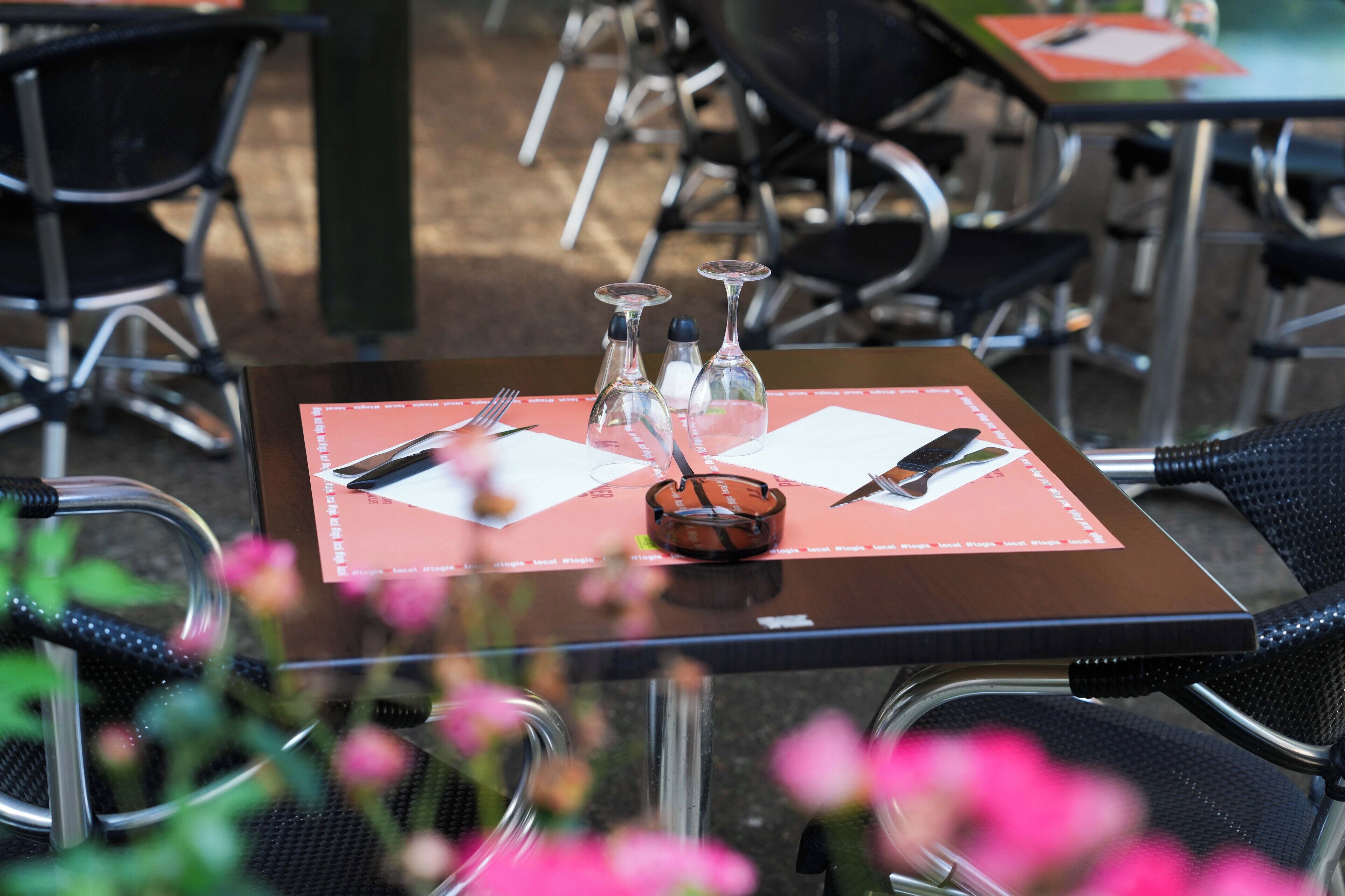 Una mesa dispuesta con cubiertos, saleros y pimenteros, y una copa.