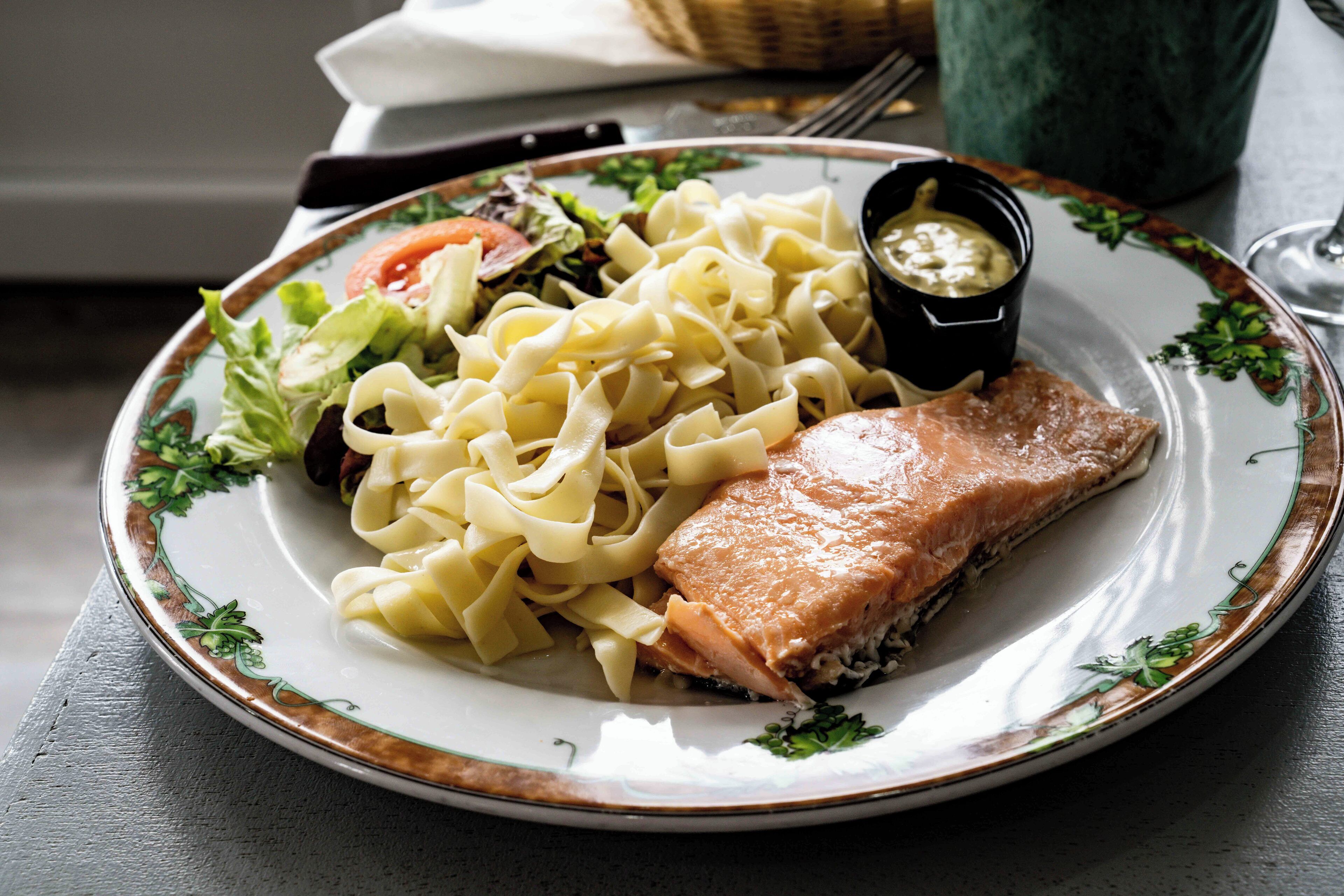 Ein Teller mit Lachs, Nudeln und Salat.