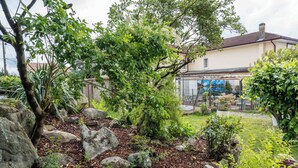 Een tuin met grote rotsen, een boom en een gebouw met een pannendak.