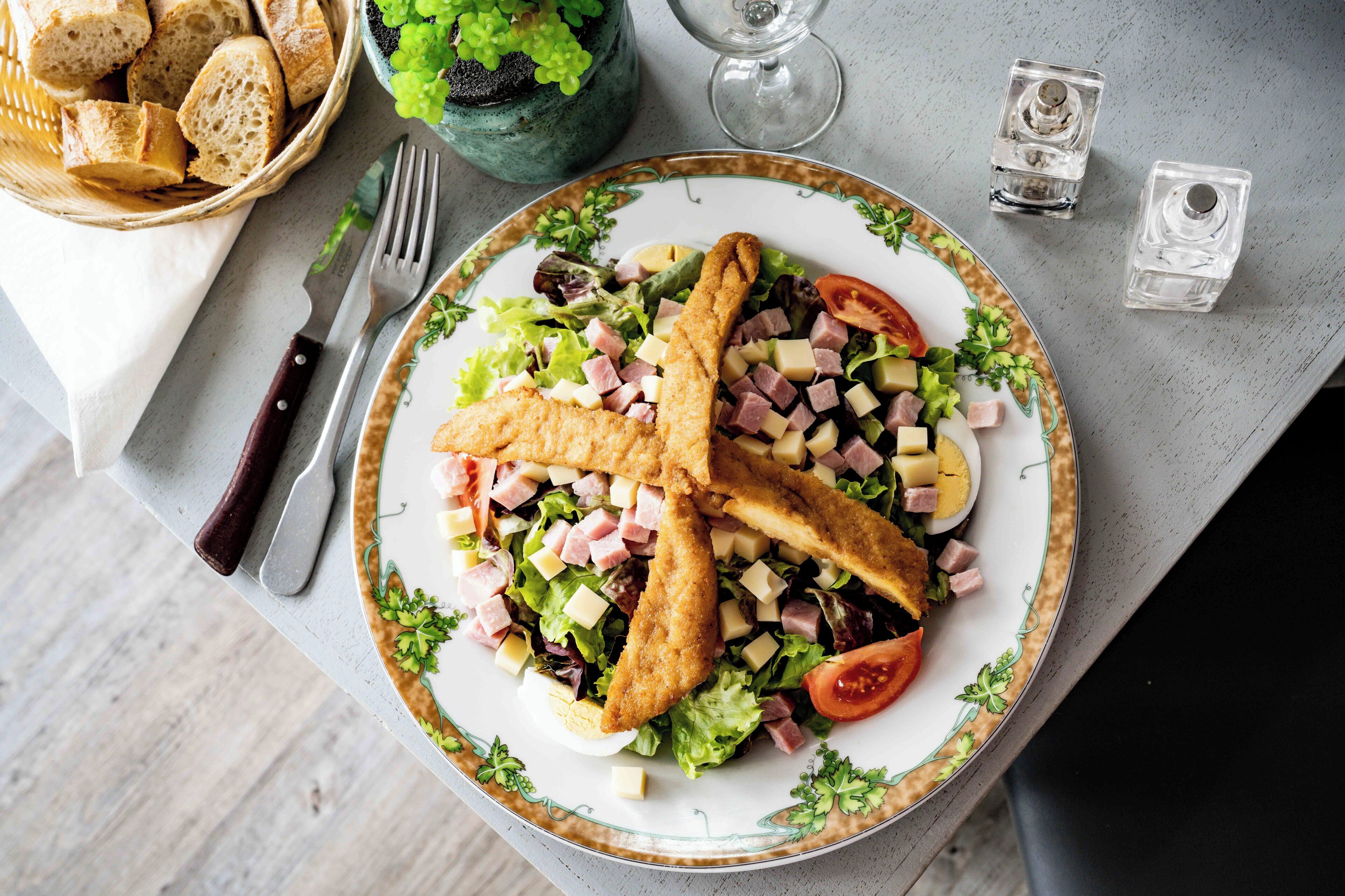 Prato de comida com pão, salada e bebida.