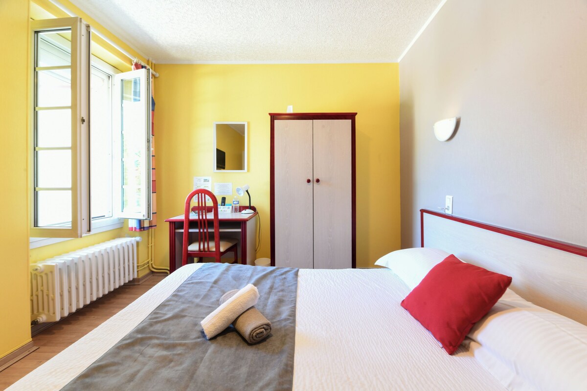 Een hotelkamer met een bed, een bureau, een stoel, een kledingkast en een raam.