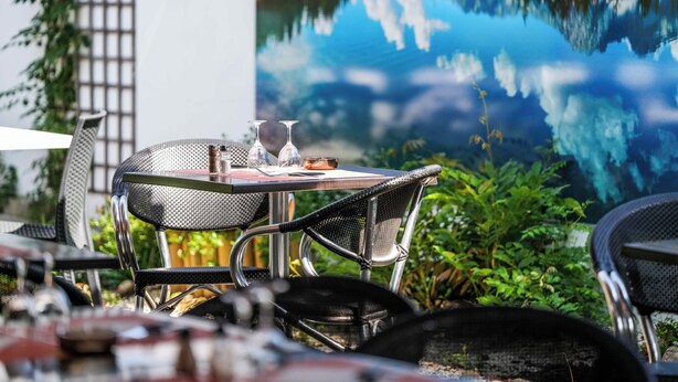 Een tafel met twee wijnglazen en een fles, voor een achtergrond van een serene meer en bergen.