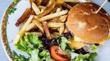 A plate with a burger, fries, lettuce, and a tomato.